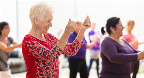 Stock Image of a older lady smiling and dancing in a dance class.