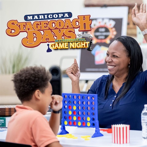 A woman and a boy enjoy a game of Connect Four, with the woman smiling and raising her hands in excitement, while the boy appears thoughtful.