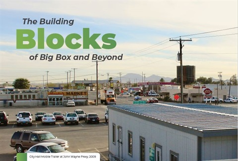 A small town scene with parked cars, boxy buildings, and distant mountains. Text reads 