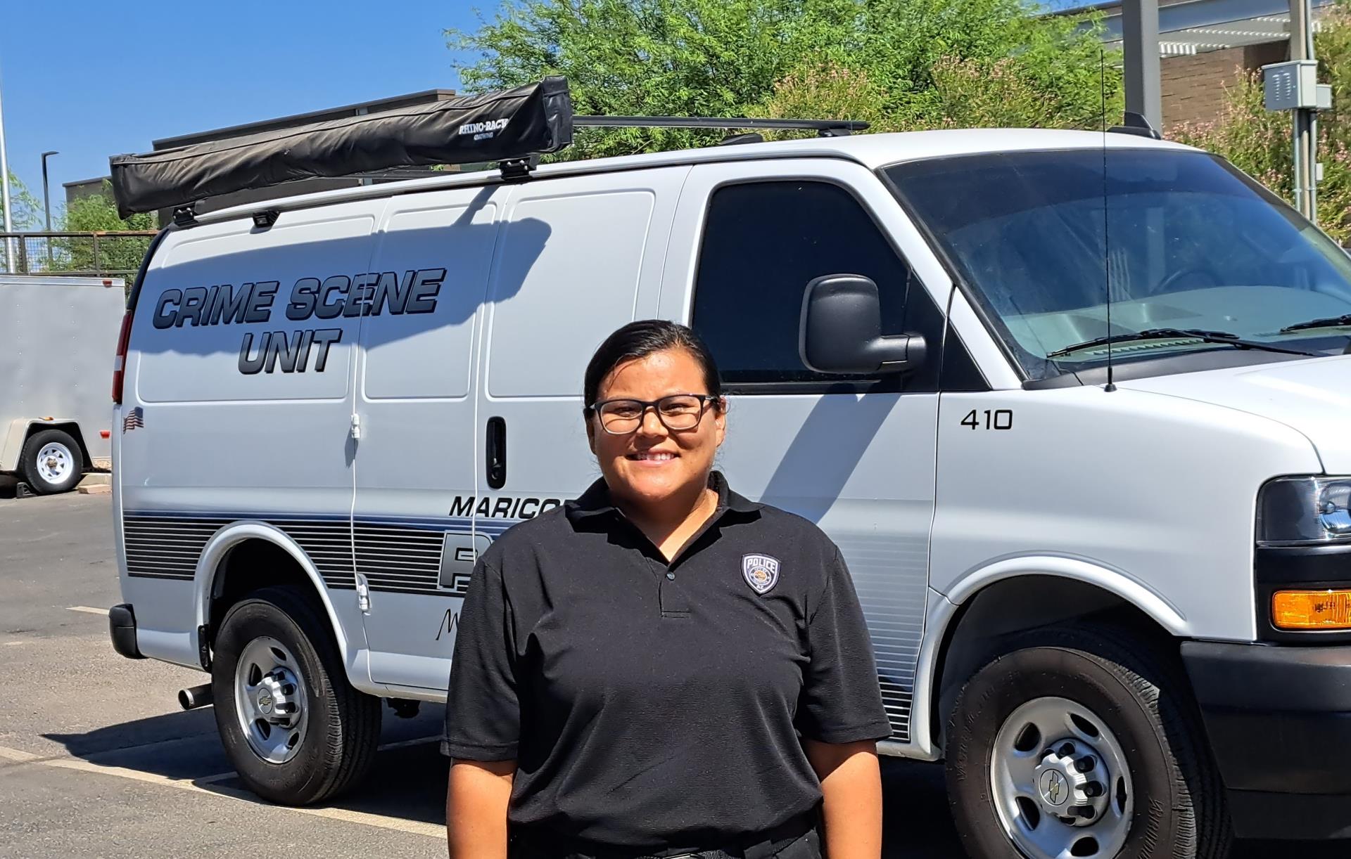 A person in a black uniform stands smiling in front of a white 