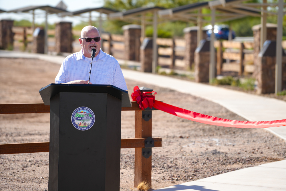 Man in sunglasses speaking at a podium with a 