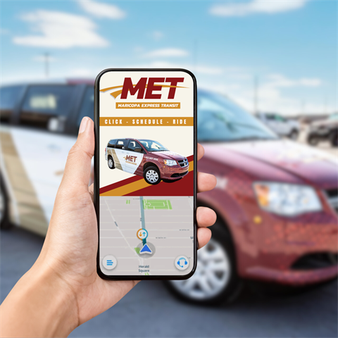 Close-up of a smartphone displaying a Maricopa Express Transit app with a van image, in front of a matching parked van, under a clear blue sky.