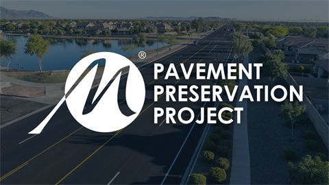 Aerial view of a freshly paved road lined with trees and houses by a lake. Overlaid text reads 