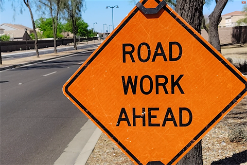 Orange diamond-shaped road sign with 